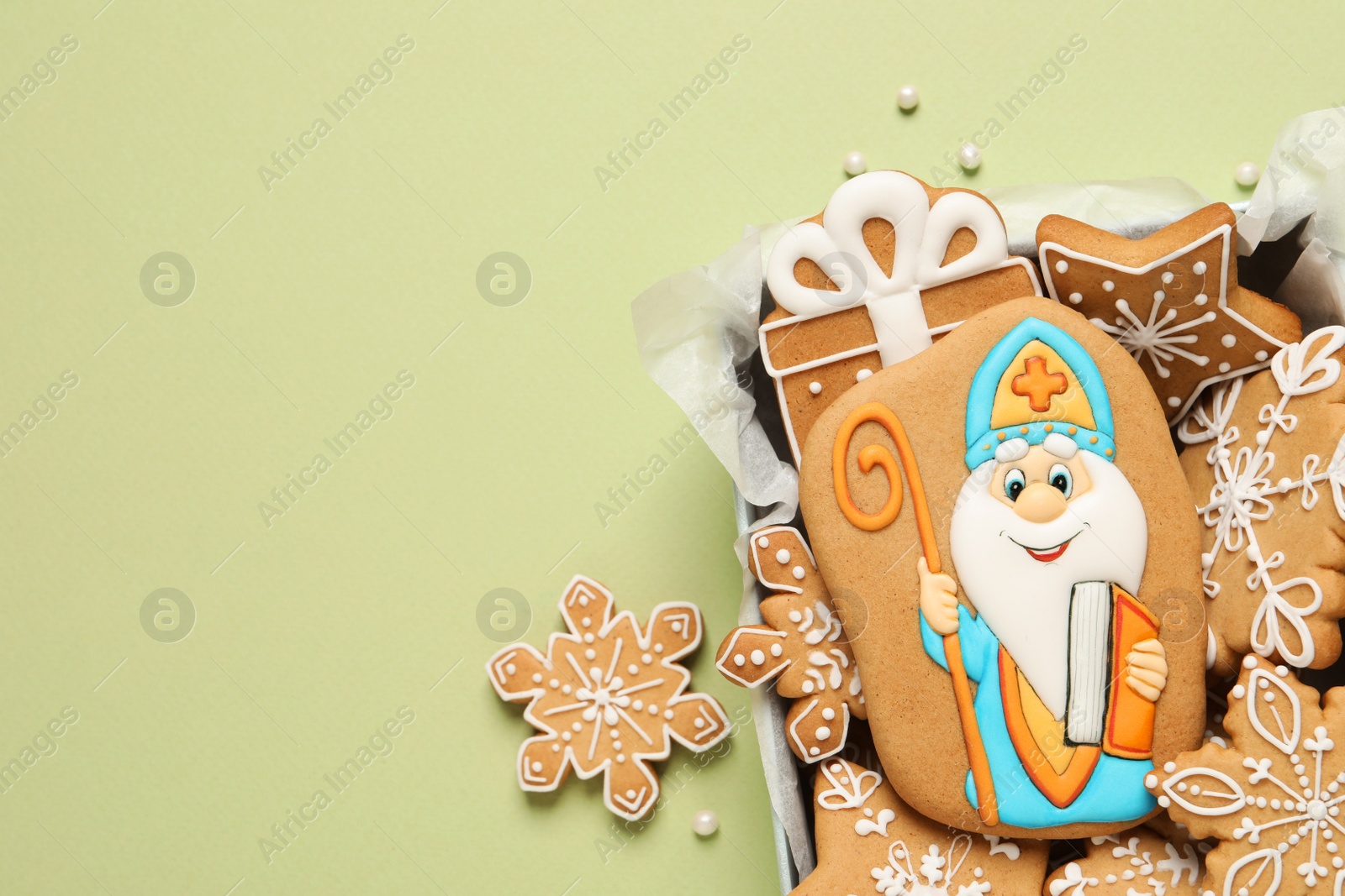 Photo of Tasty gingerbread cookies on light green background, flat lay. St. Nicholas Day celebration