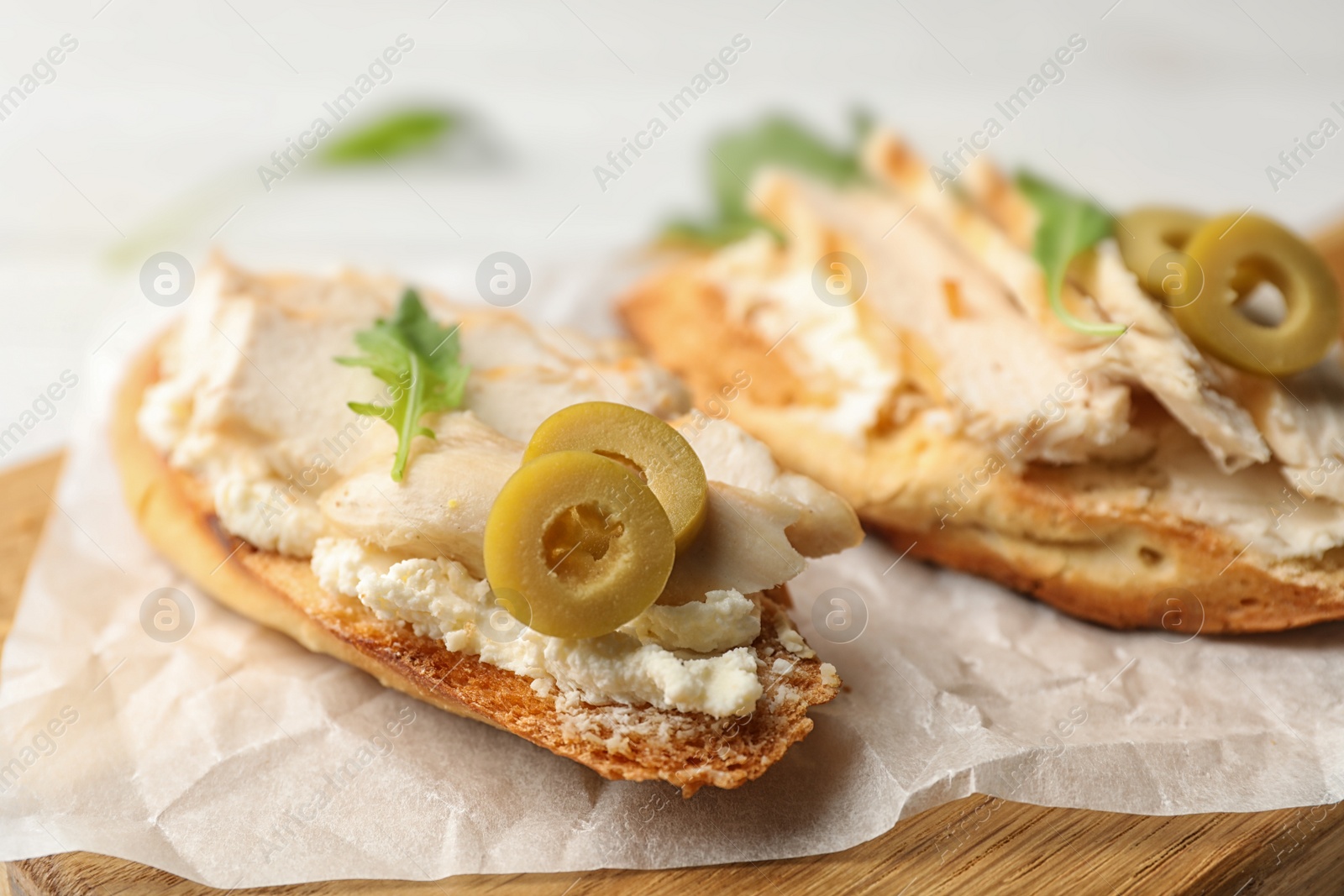 Photo of Board with delicious chicken bruschettas on table, closeup