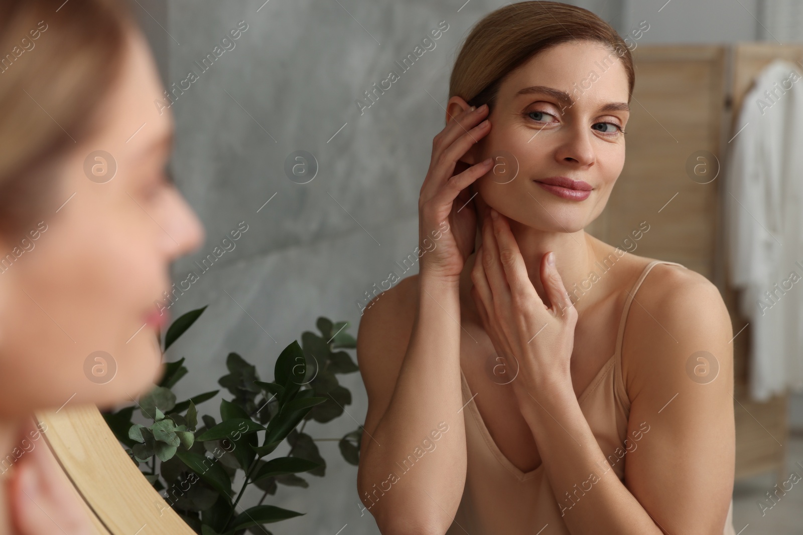 Photo of Woman massaging her face near mirror in bathroom