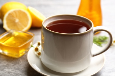 Photo of Tea with honey and lemon on grey table, closeup