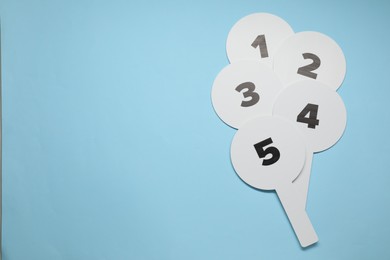 Auction paddles with numbers on light blue background, top view. Space for text