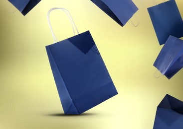 Image of Hot sale. Blue shopping bags in air on golden gradient background