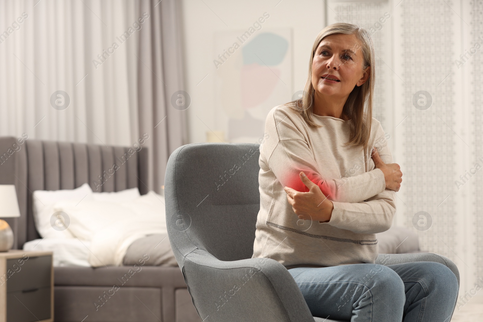 Image of Senior woman suffering from pain in elbow indoors