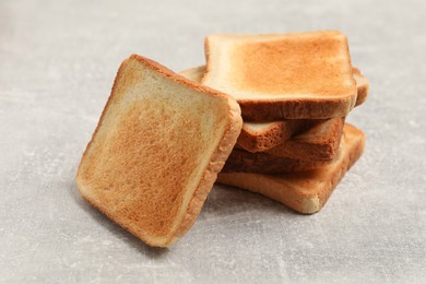 Slices of tasty toasted bread on light grey table