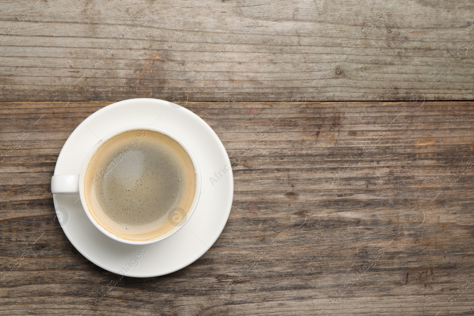 Photo of Aromatic coffee in cup on wooden table, top view. Space for text