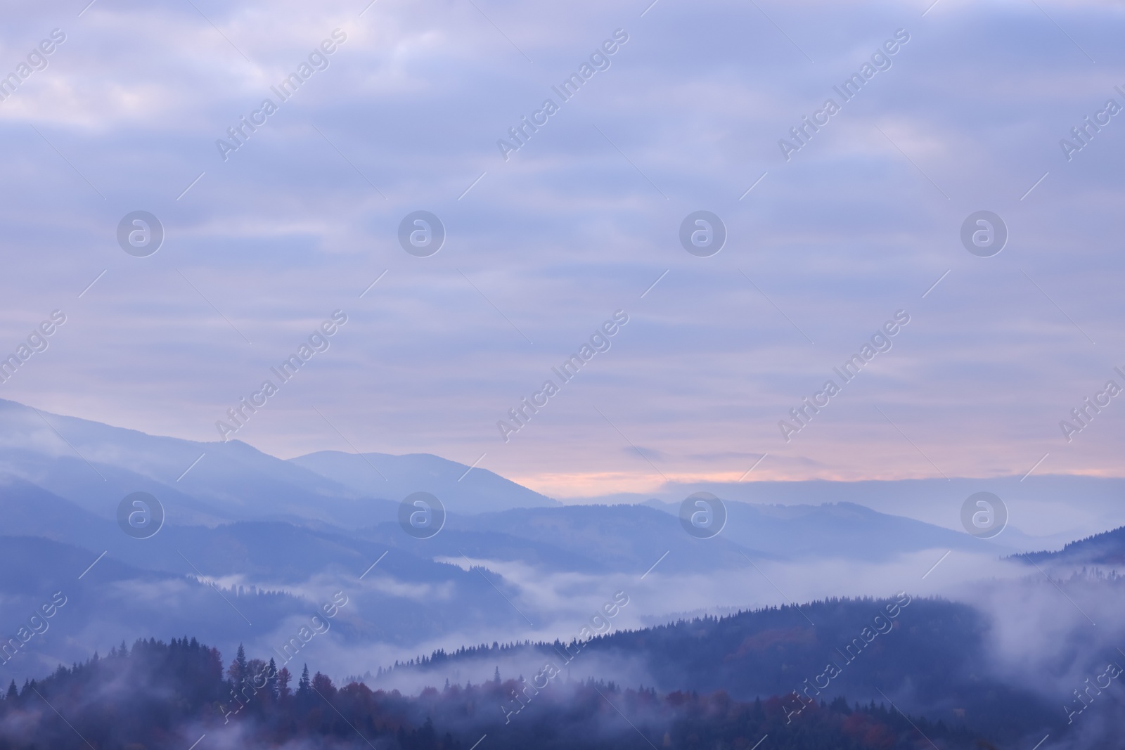 Photo of Beautiful view of mountains covered with fog and cloudy sky during sunrise