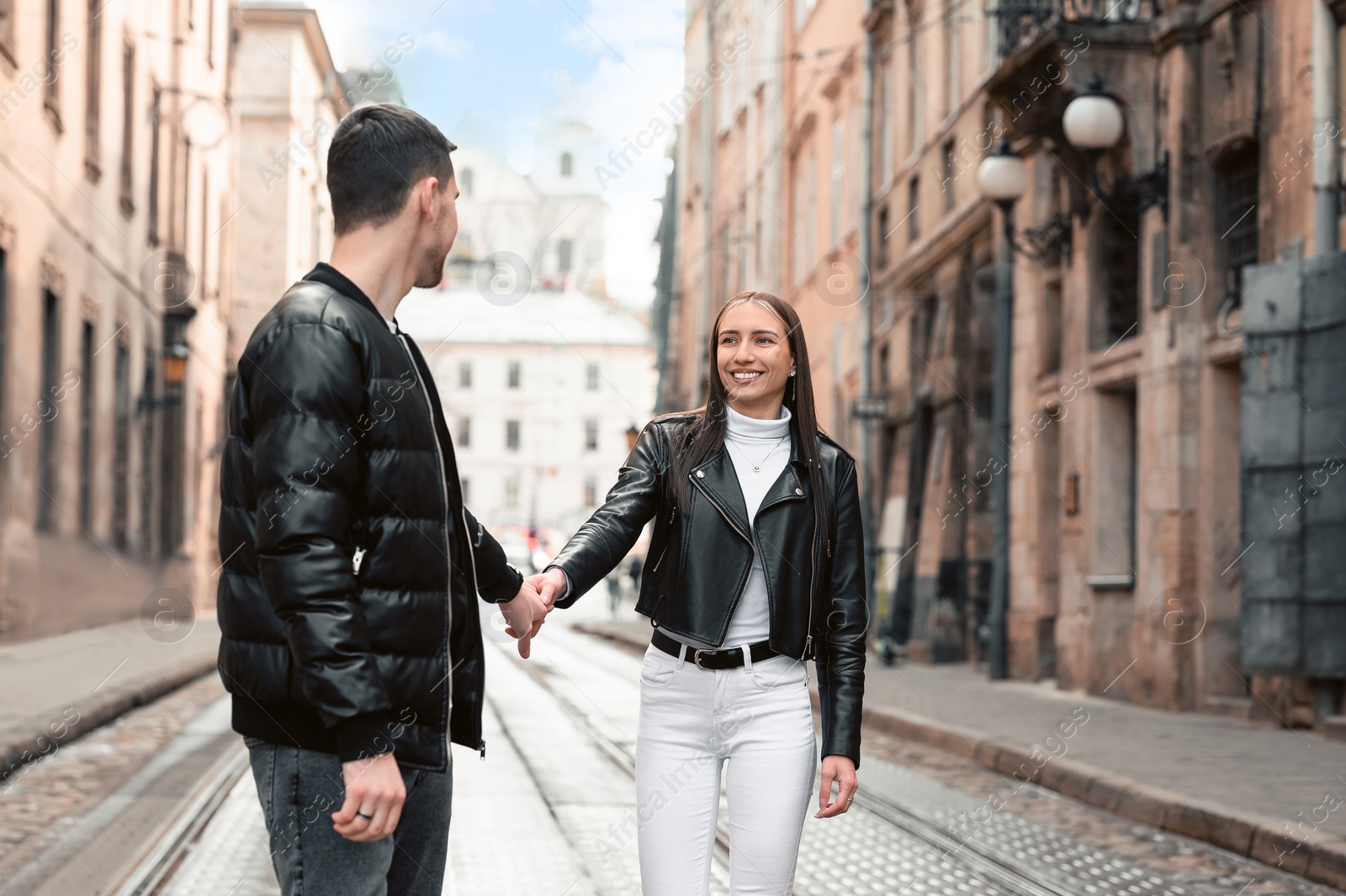 Photo of Lovely young couple walking along tram track on pavement road. Romantic date