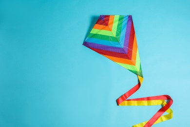Photo of Bright rainbow kite on light blue background, top view. Space for text