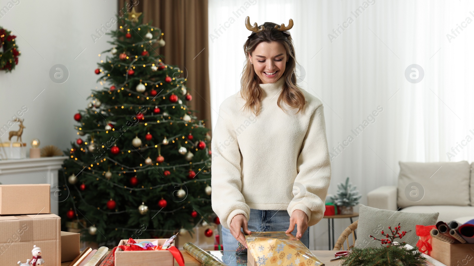 Photo of Beautiful young woman wrapping Christmas gift at home