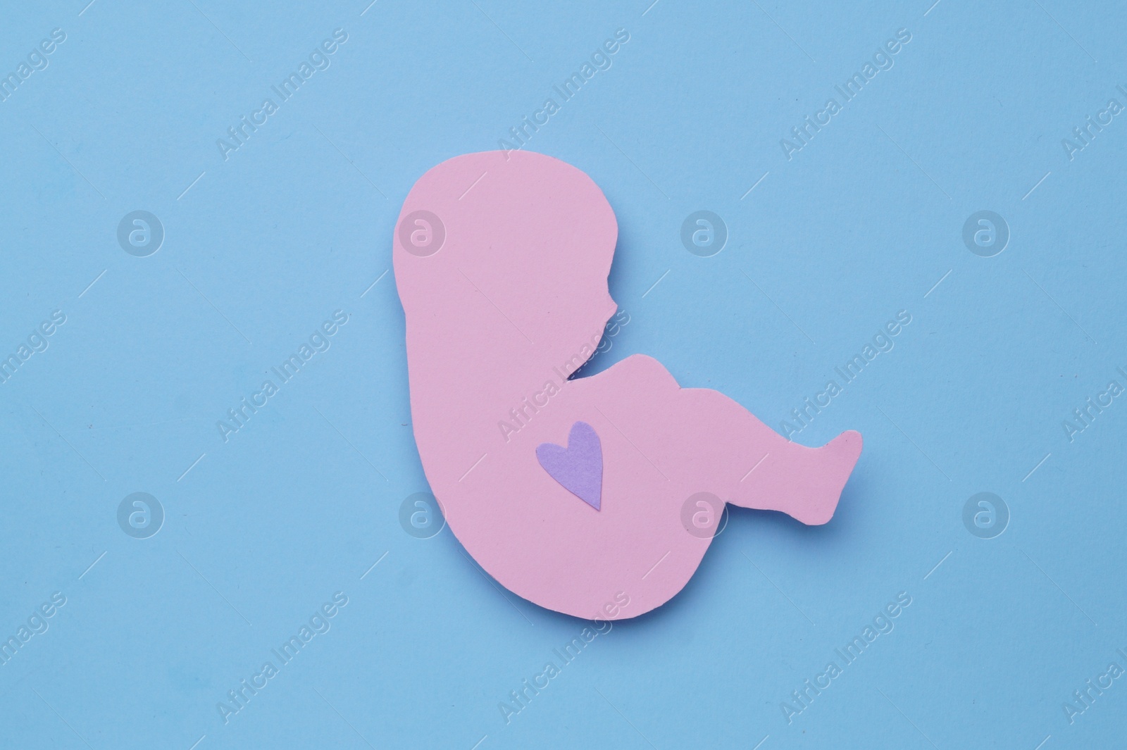 Photo of Newborn paper figure on light blue background, top view