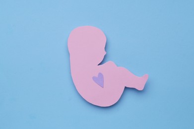 Photo of Newborn paper figure on light blue background, top view