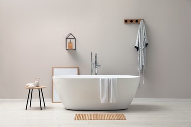Photo of Modern ceramic bathtub near light wall indoors