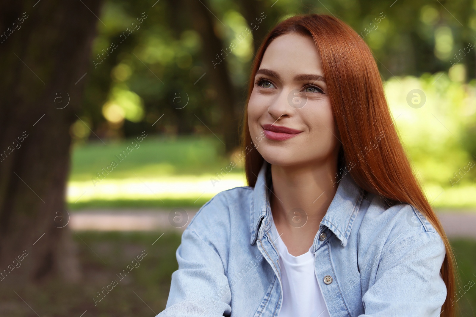 Photo of Portrait of beautiful young woman with red hair outdoors. Space for text. Attractive lady posing for camera