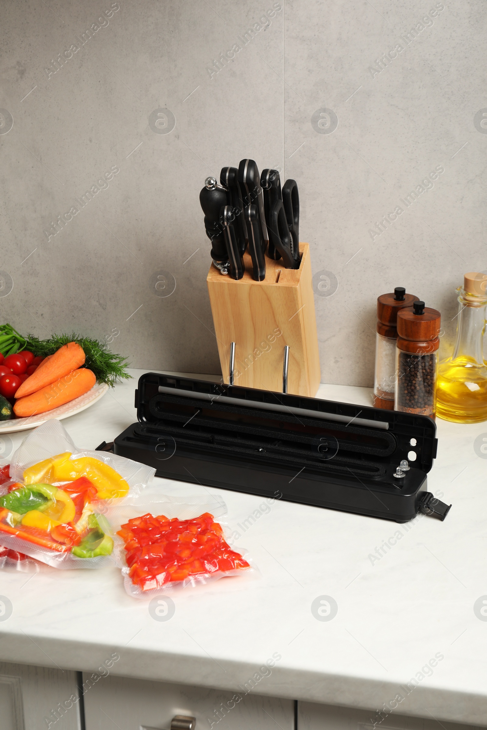 Photo of Sealer for vacuum packing and different products on white table indoors