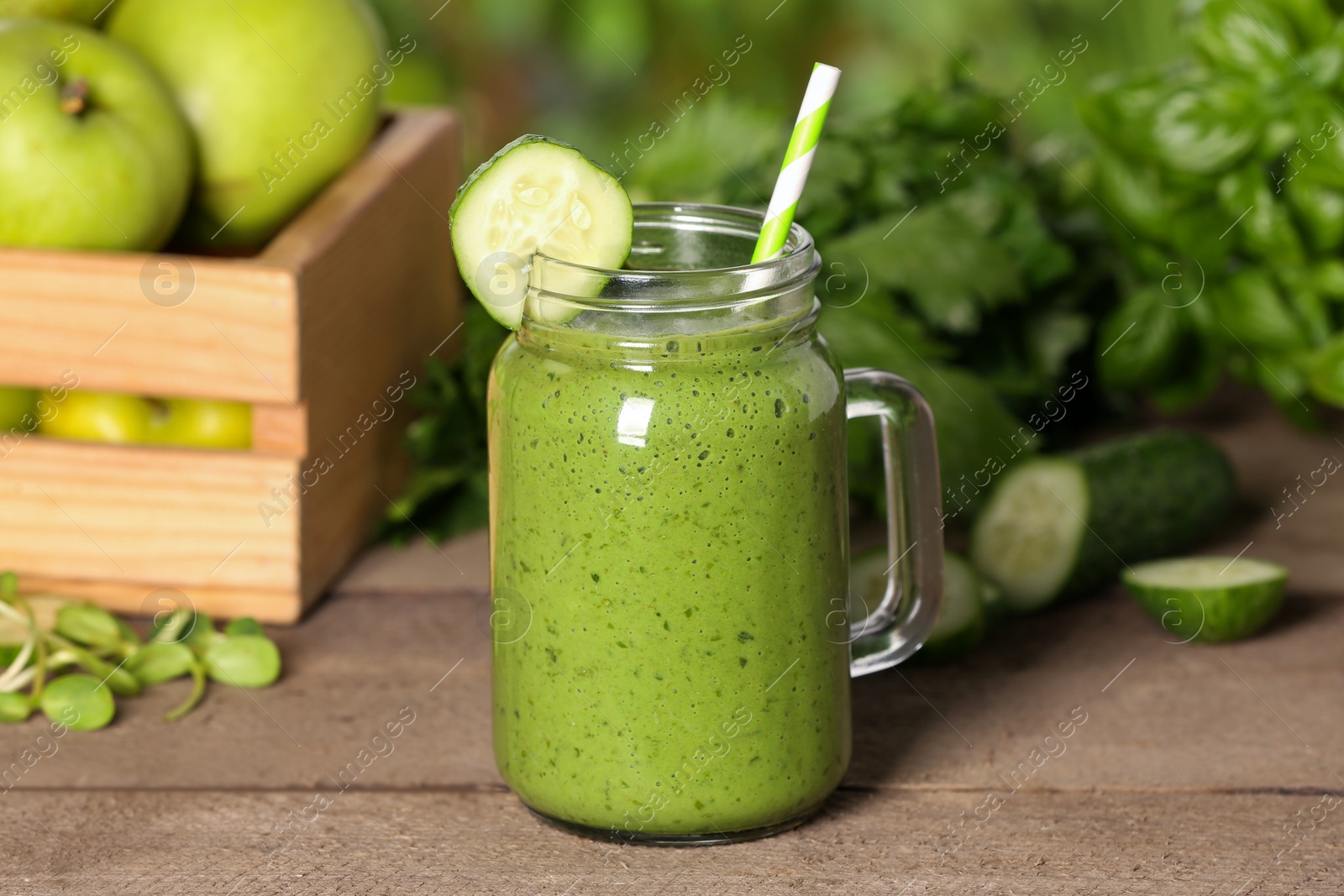 Photo of Mason jar of fresh green smoothie and ingredients on wooden table outdoors