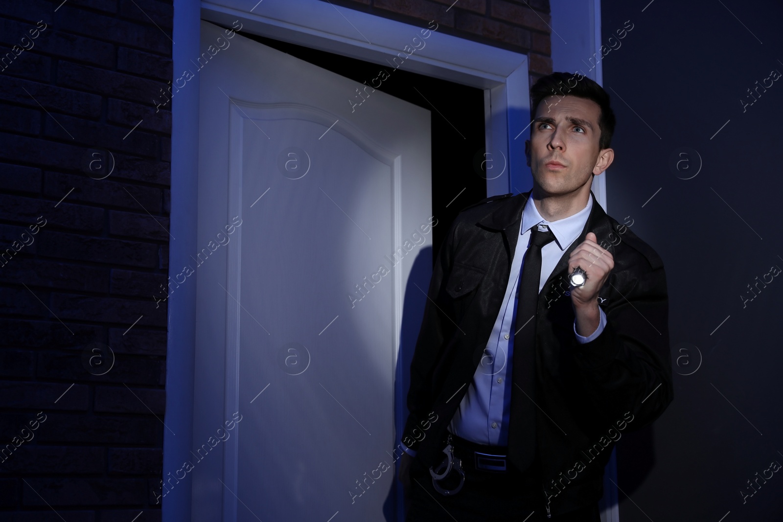 Photo of Male security guard with flashlight in dark room