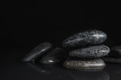 Stones in water on black background, space for text. Zen lifestyle