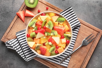 Bowl with fresh cut fruits on table, top view