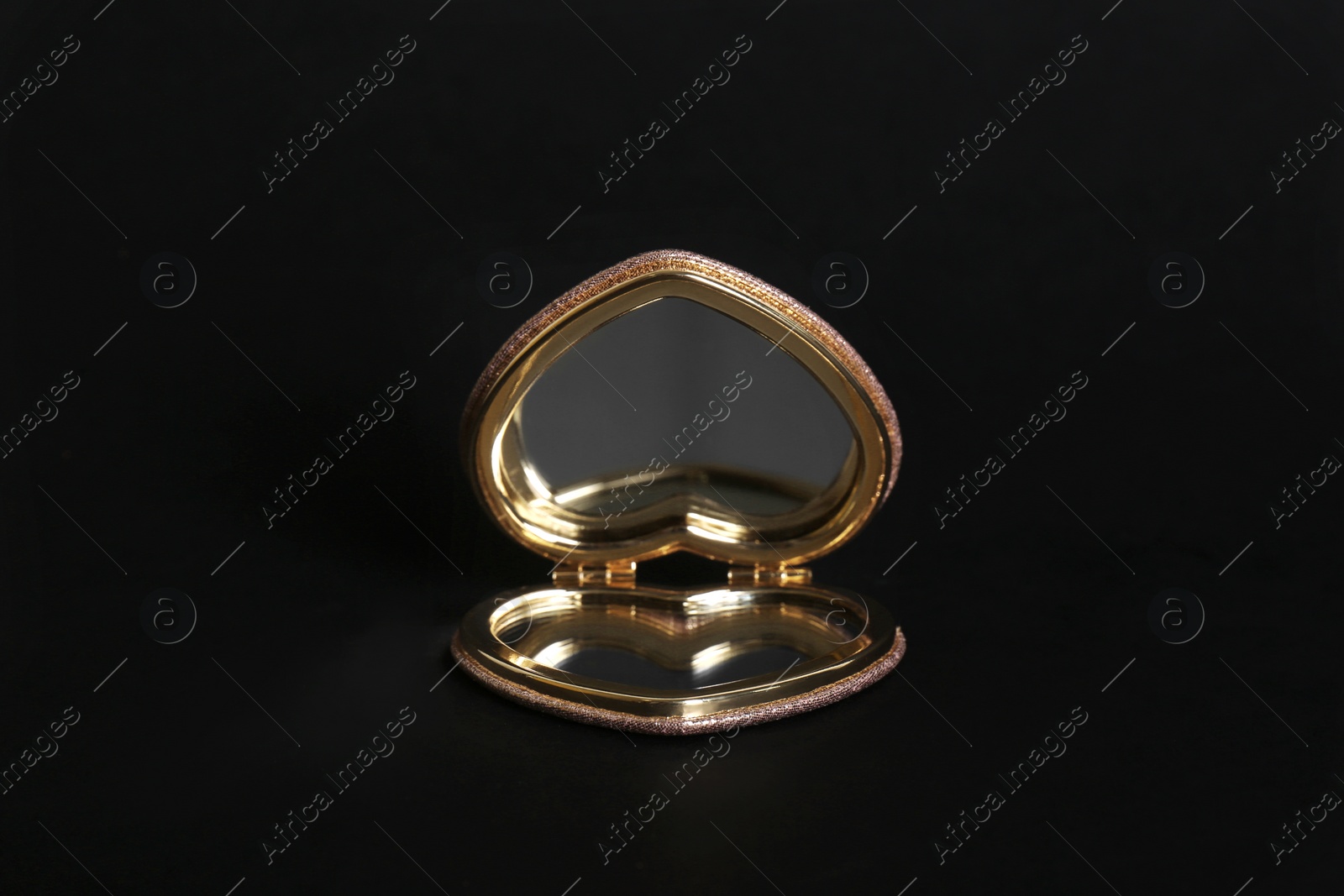 Photo of Heart shaped gold pocket mirror on black background