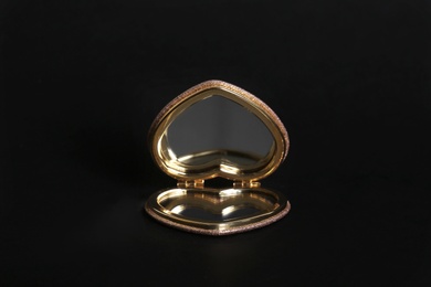 Heart shaped gold pocket mirror on black background