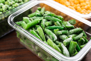 Photo of Frozen cut green beans on wooden table, closeup. Vegetable preservation