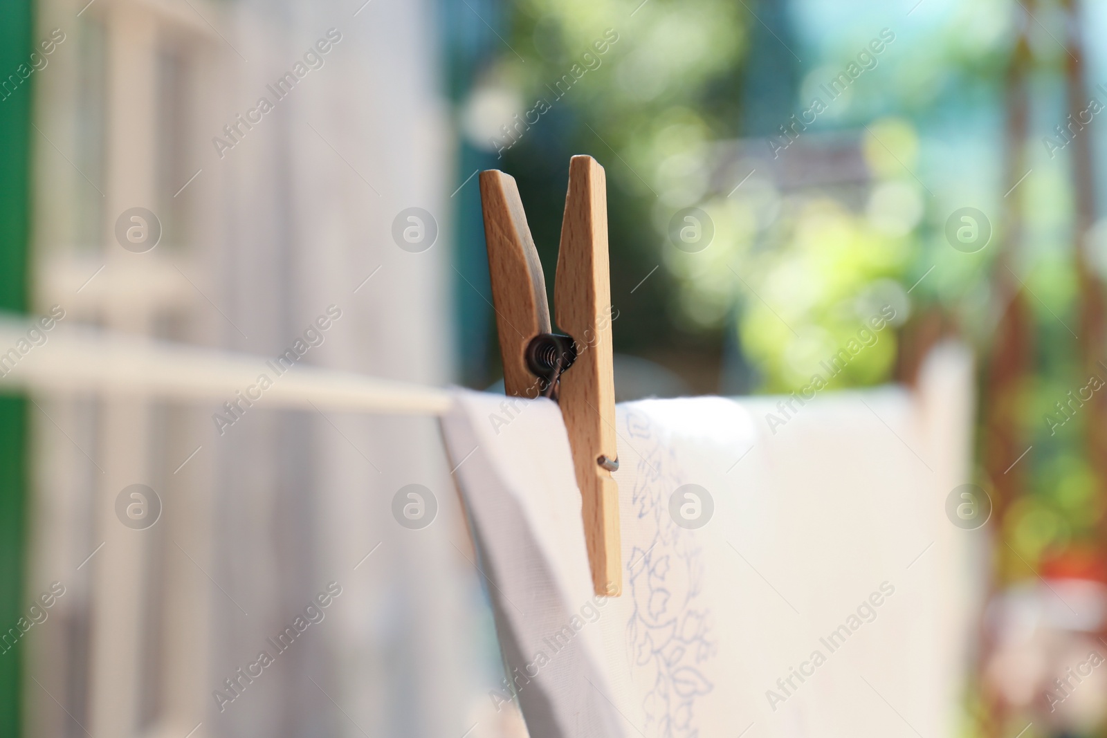 Photo of Washing line with clean laundry and clothespin outdoors, closeup