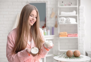 Young woman with coconut oil for hair in bathroom