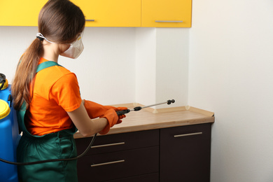 Pest control worker spraying pesticide in kitchen