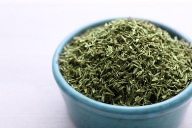 Ceramic bowl with dried thyme on white wooden table, closeup