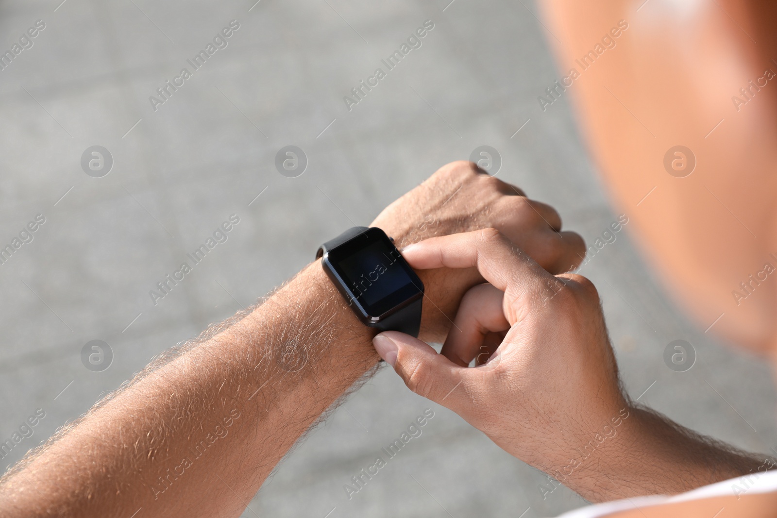 Photo of Man checking fitness tracker after training outdoors, closeup