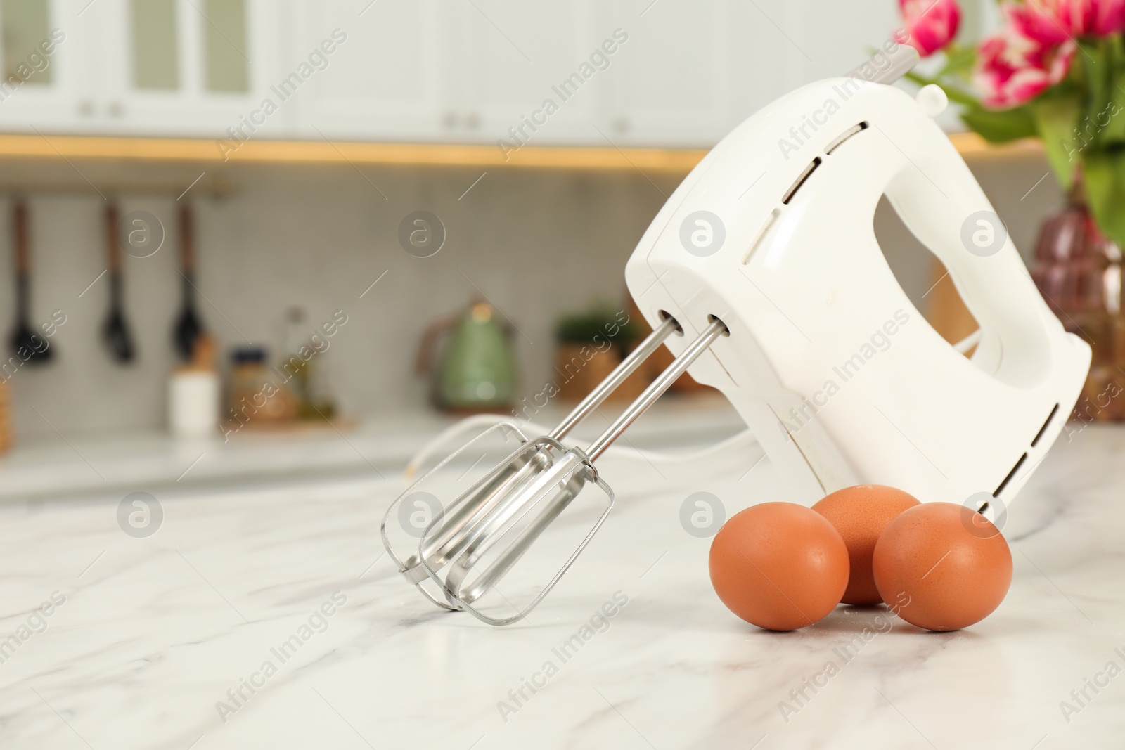 Photo of Modern mixer and eggs on white marble table in kitchen, space for text