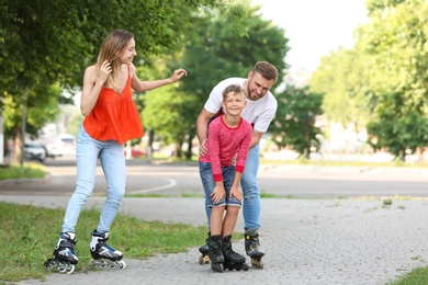 Young happy family roller skating on city street