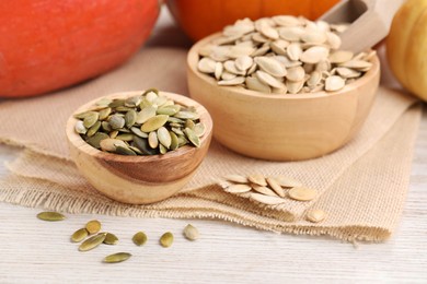 Photo of Bowls with pumpkin seeds on light wooden table