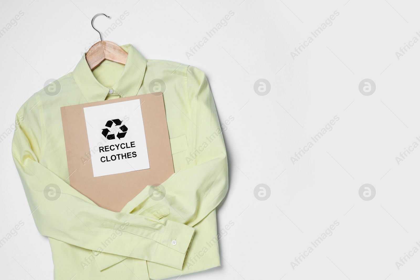 Photo of Shirt and card with recycling symbol on white background, top view. Space for text