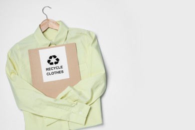 Photo of Shirt and card with recycling symbol on white background, top view. Space for text