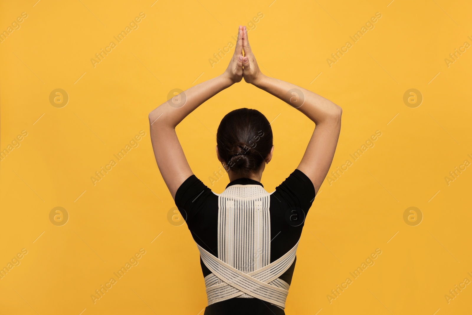 Photo of Woman with orthopedic corset on orange background, back view