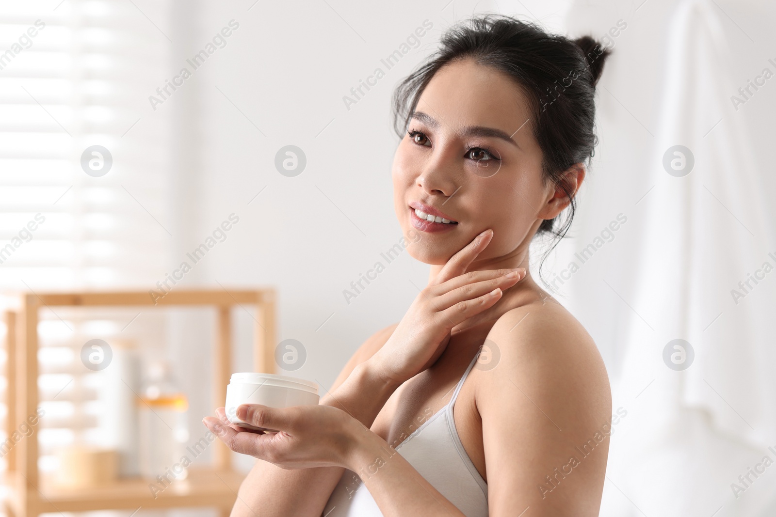 Photo of Happy woman applying body cream at home