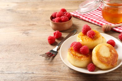 Delicious cottage cheese pancakes with raspberries on wooden table. Space for text