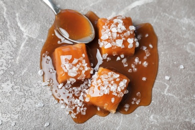 Delicious candies with caramel sauce and salt on table