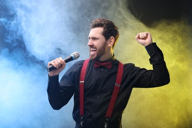 Photo of Emotional man with microphone singing in color lights