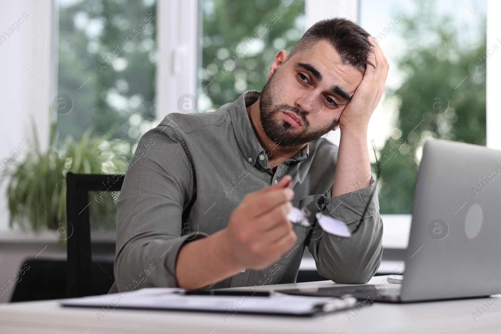 Photo of Overwhelmed man sitting at table in office