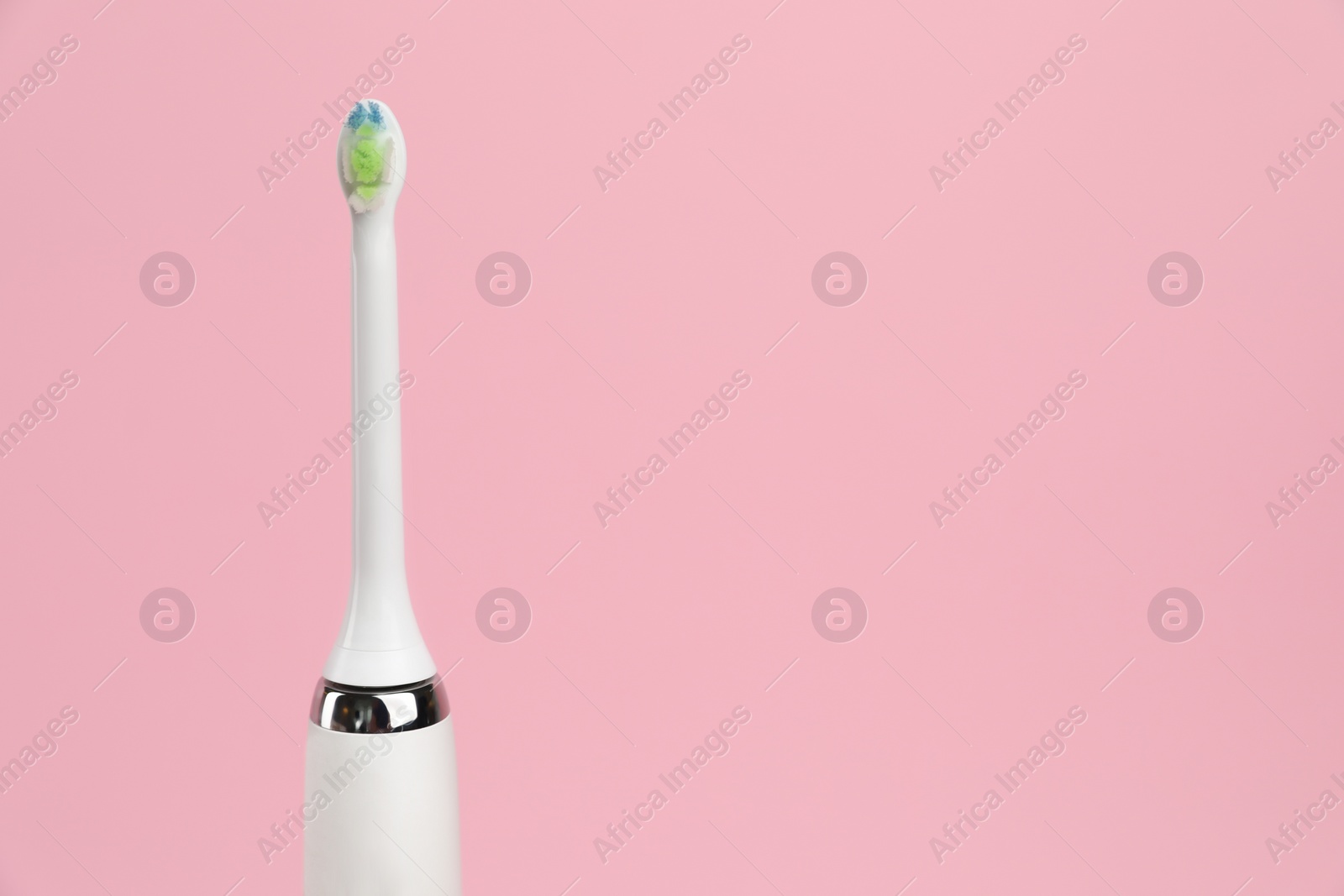 Photo of Electric toothbrush on pink background, space for text