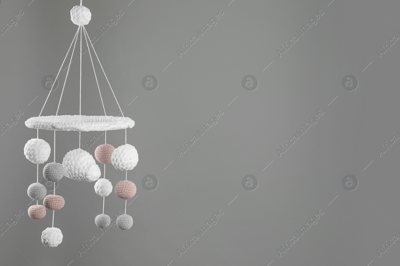 Photo of Cute baby crib mobile on grey background. Space for text