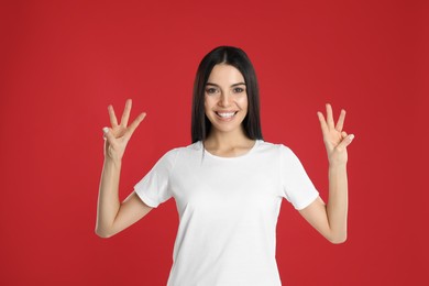 Photo of Woman showing number six with her hands on red background
