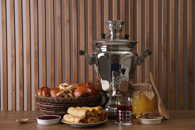 Photo of Traditional Russian samovar with treats on wooden table