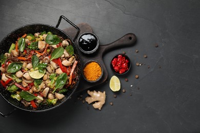 Photo of Stir-fry. Tasty noodles with meat in wok and ingredients on grey textured table, flat lay