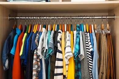 Hangers with teenage clothes on rack in wardrobe, closeup