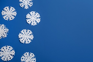 Many paper snowflakes on blue background, flat lay. Space for text