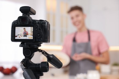 Food blogger recording video in kitchen, focus on camera