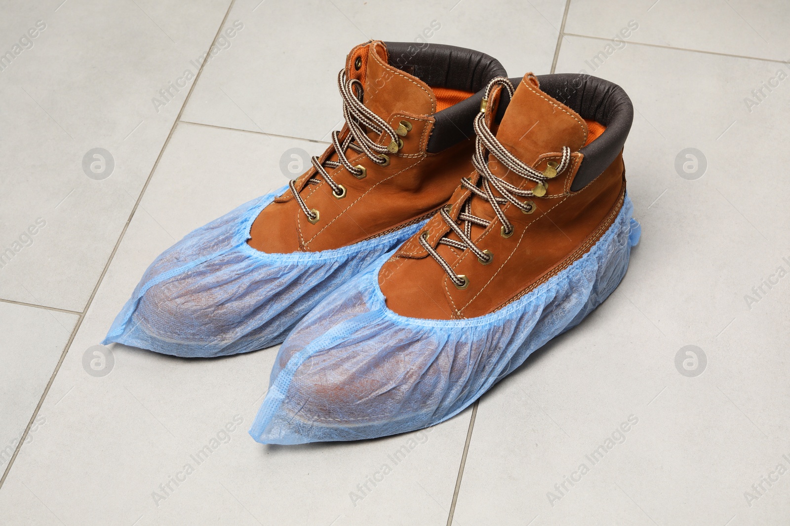 Photo of Men`s boots in blue shoe covers on light floor